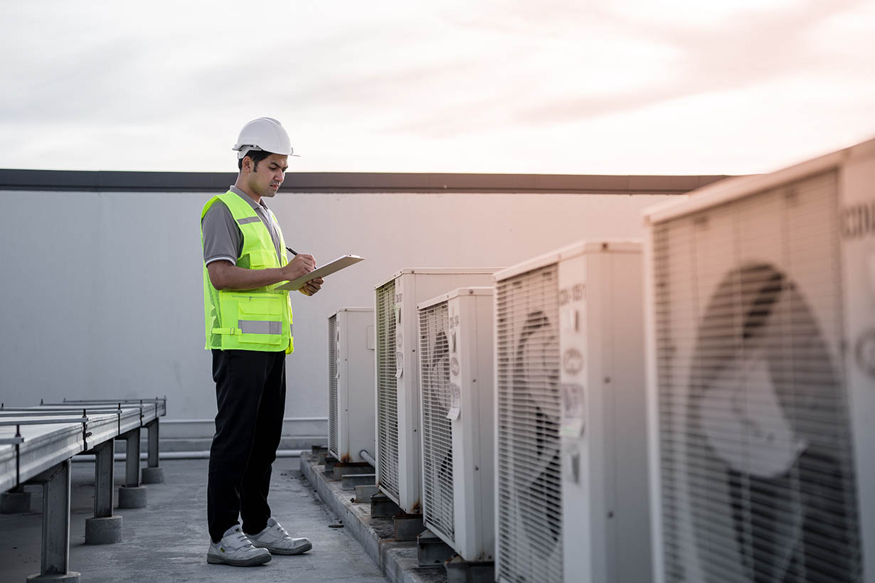Factory engineers walking and checking the cooling system of the factory. Fore man records the condition of the compressor before maintenance according maintenance plan. commercial HVAC technician performing service