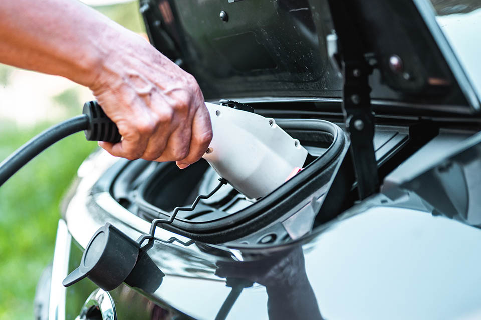 Human hand is holding electric car charging connect to electric car Person plugging in an EV Charger