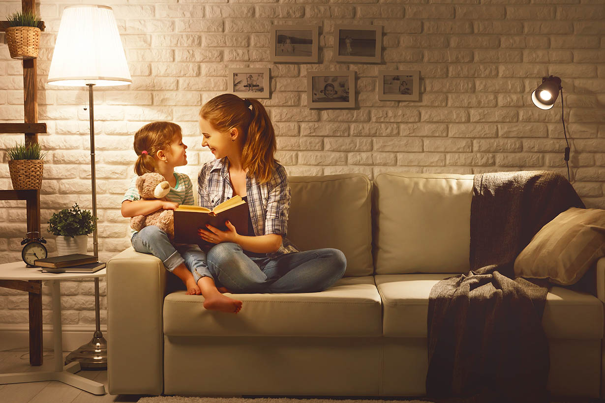 mother reading to her daughter on the couch