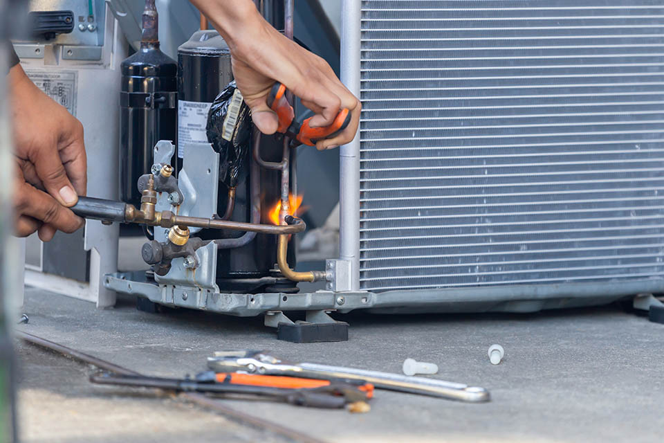 Close up of Air Conditioning Repair team use fuel gases and oxygen to weld or cut metals, Oxy-fuel welding and oxy-fuel cutting processes, repairman on the floor fixing air conditioning system Close-up of an HVAC technician repairman on the floor fixing heat pump system with welding tools
