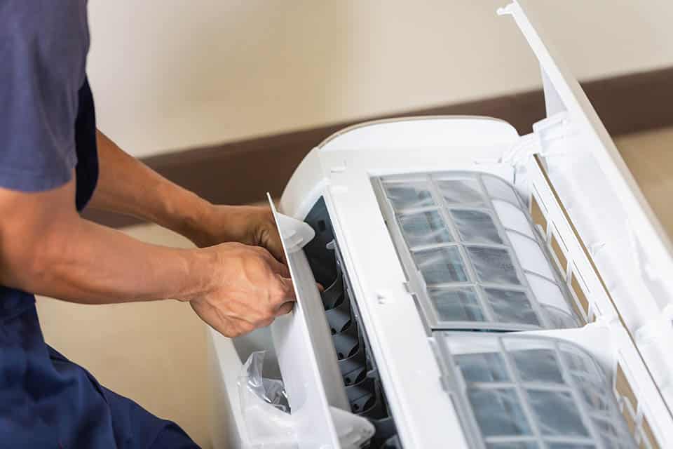 Technician man installing an air conditioning in a client house, Young repairman fixing air conditioner unit, Maintenance and repairing concepts Technician performing a mini split repair in a home