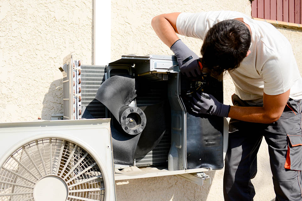 young man electrician installer working on outdoor compressor unit air conditioner at a client’s home HVAC technician working on outdoor compressor unit in mini split