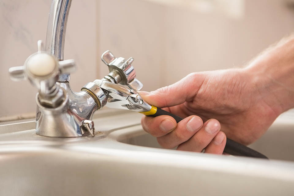 Man fixing tap with pliers plumbing FaucetRepairInstall Hero 2 960x640 1