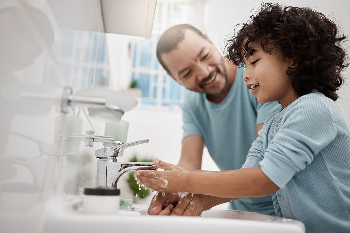 Shot of a father helping his son wash his hands and face at a tap in a bathroom at home Picture of a father helping his son wash his hands and face at a tap in a bathroom