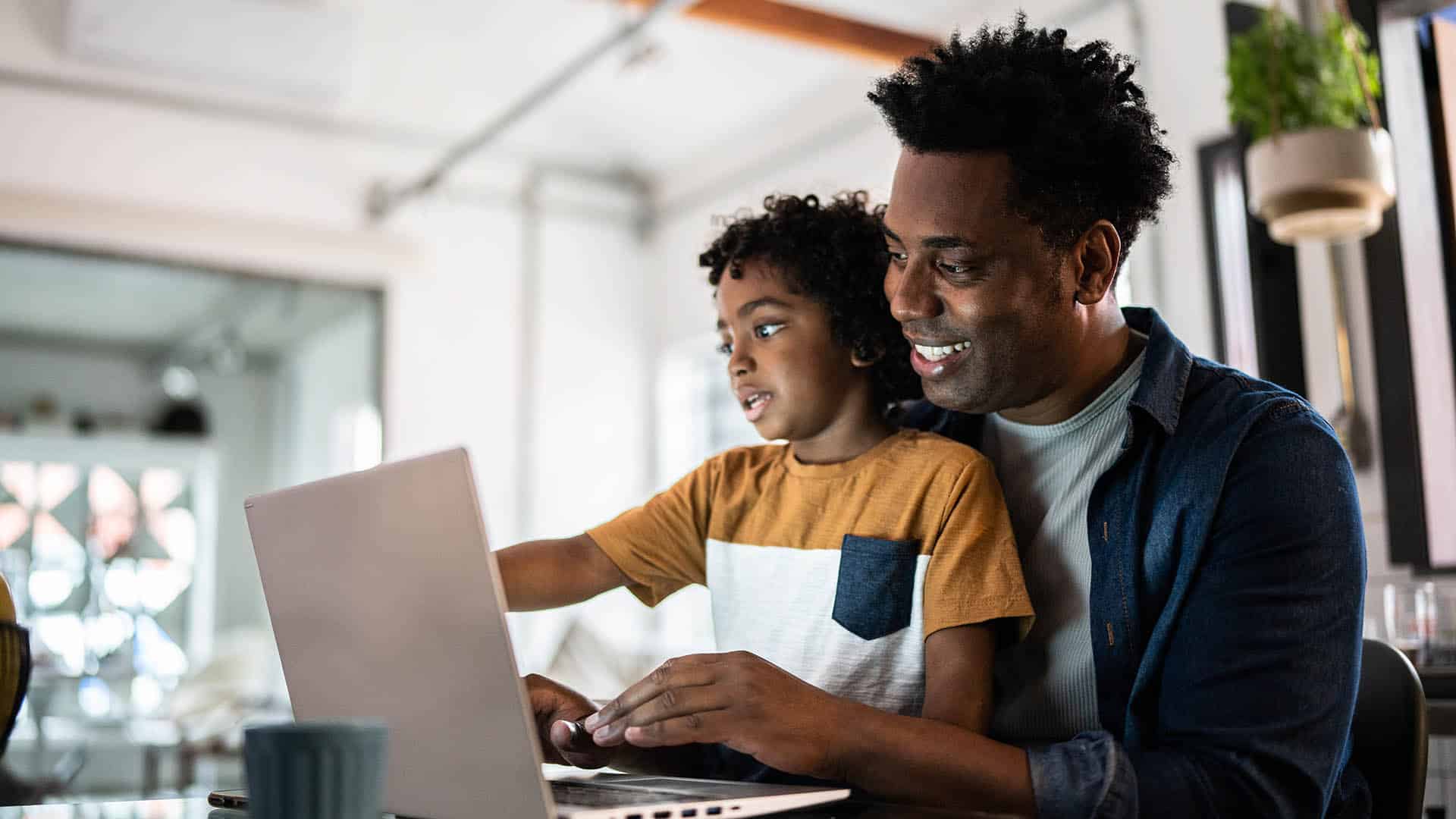 Father using the laptop with son at home father and son looking at a laptop together